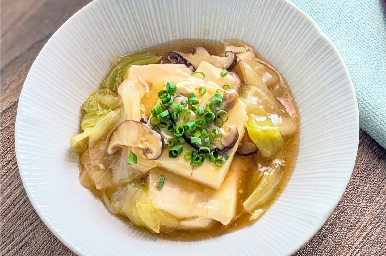 豆腐ときのこのあんかけ料理が白い皿に盛られています。ネギがトッピングされています。