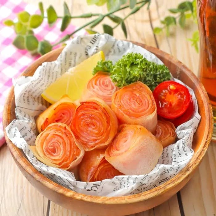 野菜とハムのロールが円形に盛り付けられたボウル内にあります。レモンのスライスとチャーブ付き。