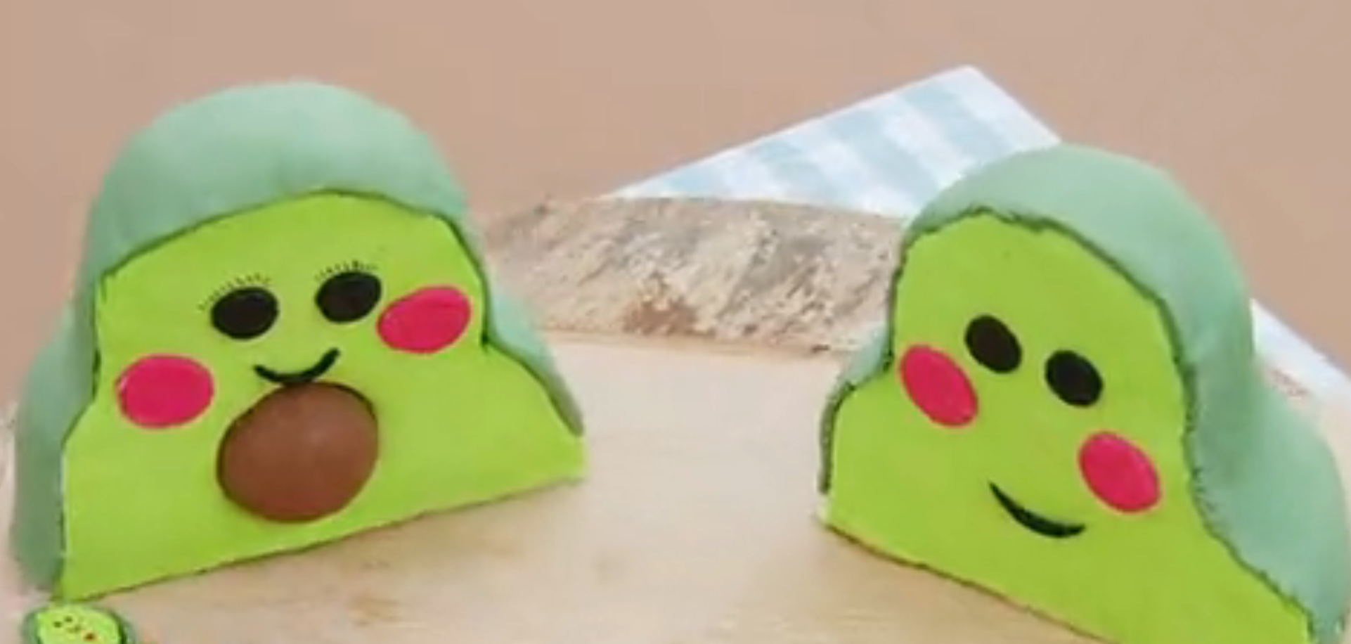 Two cute, cartoon-like green blob figures with smiling faces, one holding a brown sphere, on a light checkered surface