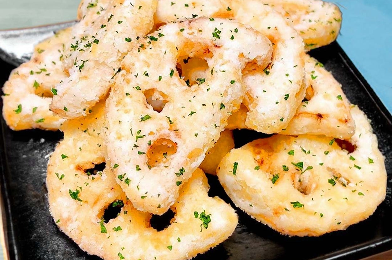 レンコンの天ぷらが黒い皿に盛られている。上に刻みパセリが振りかけられ、美味しそうに見える。