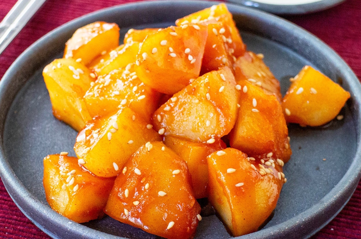 おいしそうな甘辛いタレで和えたカボチャの煮物が、丸い皿に盛られています。上には白ゴマがかかっています。