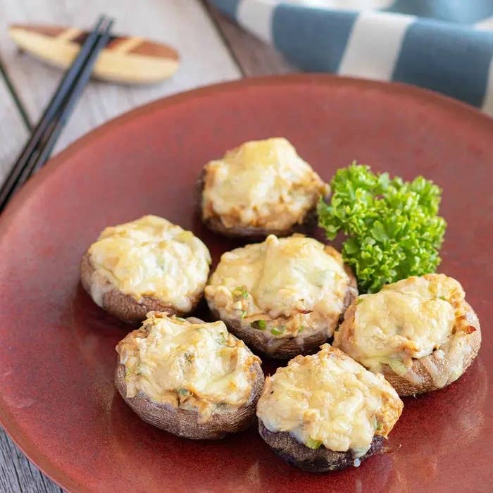 お皿に盛られた6つのチーズ焼きのしいたけ料理。パセリが添えられています。