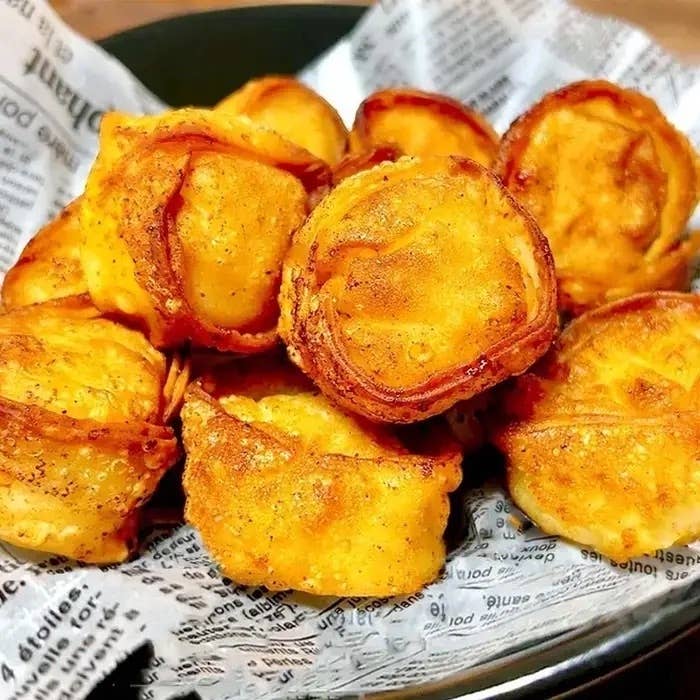 新聞紙に乗った揚げたてのキッシュのような食べ物が盛りつけられた皿。おいしそうな香ばしい焼き色。