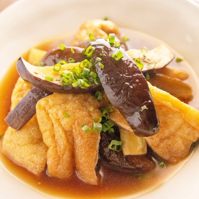 油揚げとなすの煮びたし。油揚げとなすの和風料理。刻みネギが添えられた皿に盛り付けられている。
