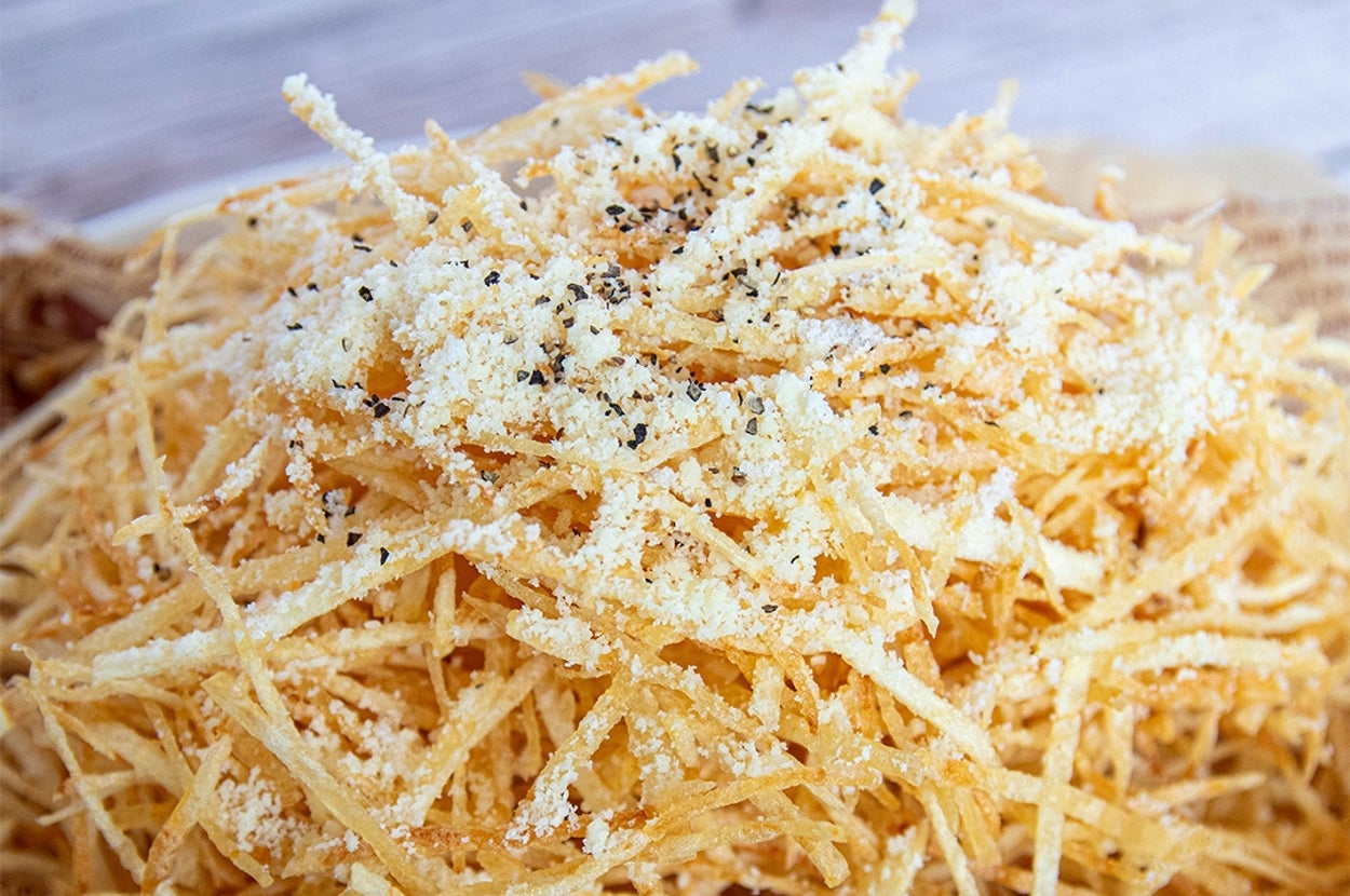 細切りポテトフライが盛られた皿。上に粉チーズと黒こしょうがかけられている。