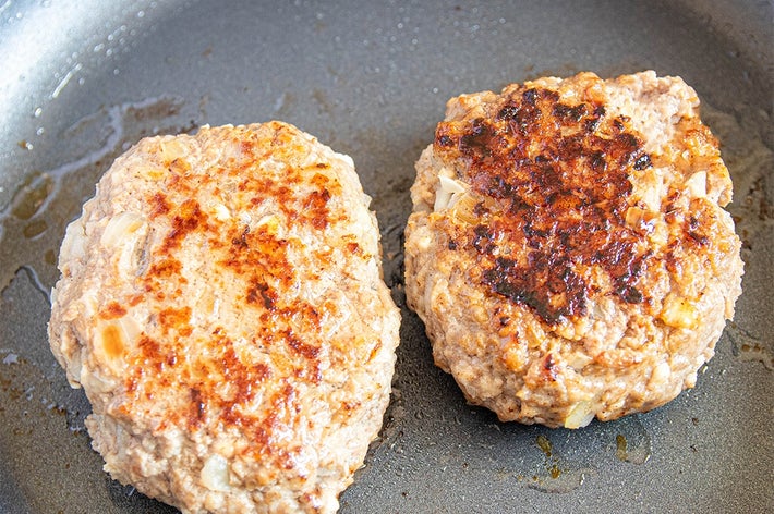 フライパンで焼かれる2つの肉のパティ。