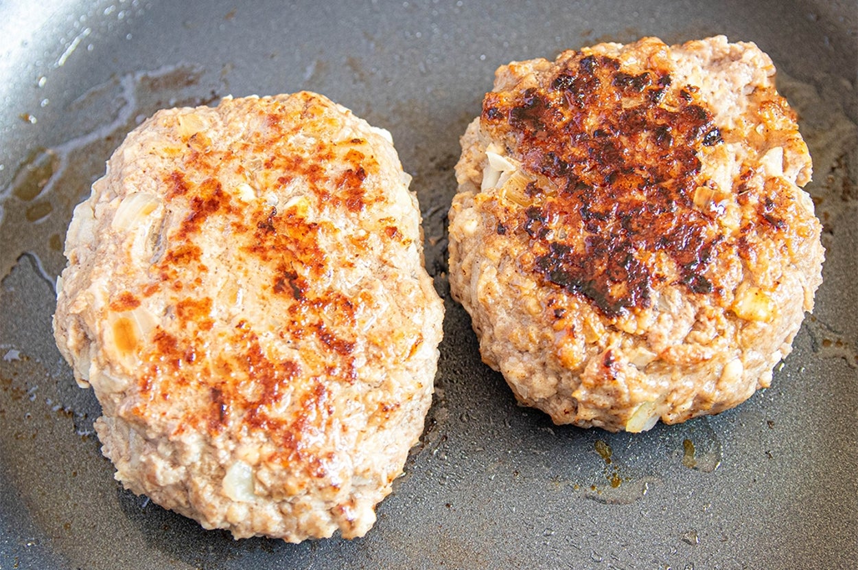 フライパンで焼かれる2つの肉のパティ。