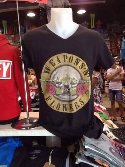 Mannequin wearing a T-shirt with a parody rock band logo featuring guns and roses labeled quotWeapons N Flowersquot displayed in a shop