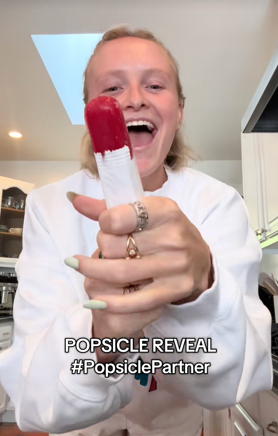 Person holding a two-tone popsicle and smiling. Text reads: "POPSICLE REVEAL #PopsiclePartner"