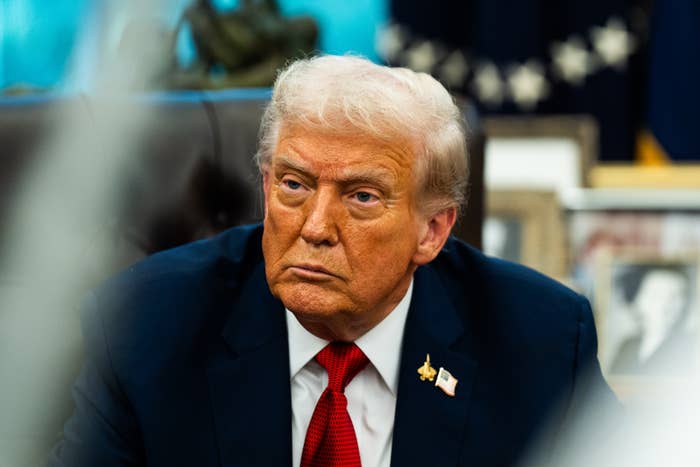 I don’t know who this is, but the image shows a person in a suit and tie, sitting in an office, looking serious