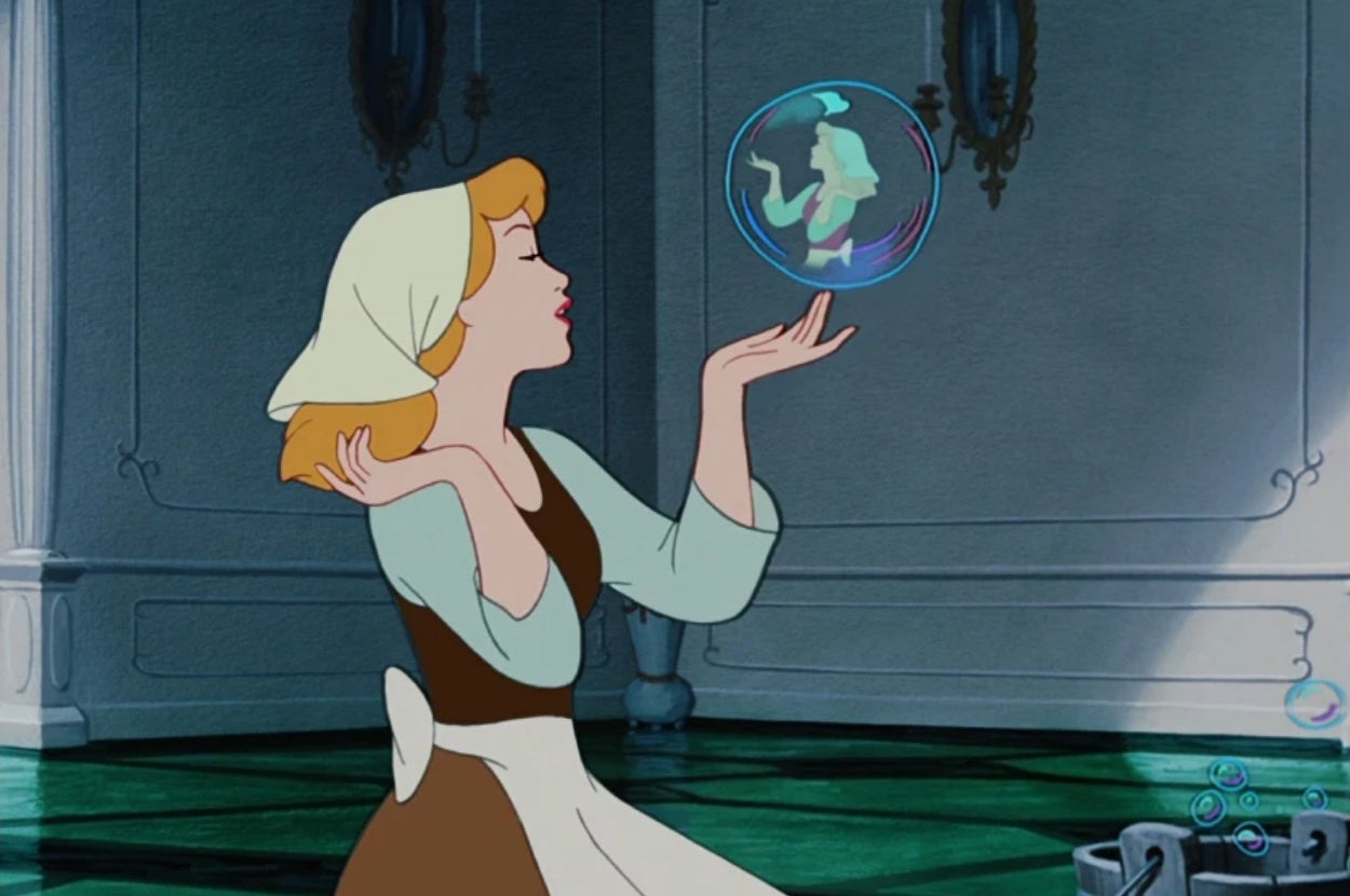 Animated character Cinderella blowing bubbles, with one reflecting her image, in a house setting
