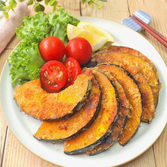 かぼちゃのフライとサラダ菜、トマト、レモンがきれいに盛り付けられたプレート。