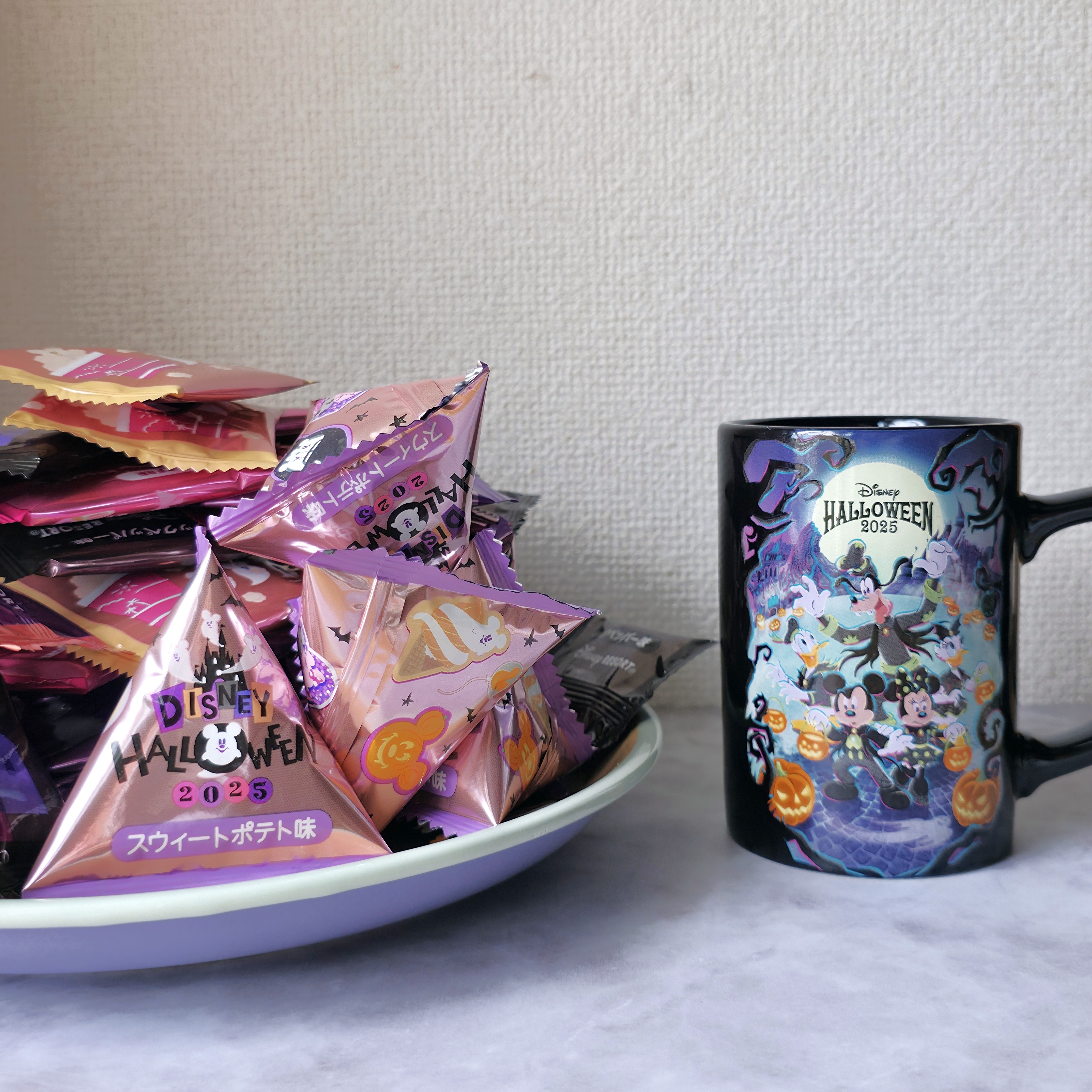 ディズニーハロウィーン2023のお菓子とマグカップがテーブルに置かれている。
