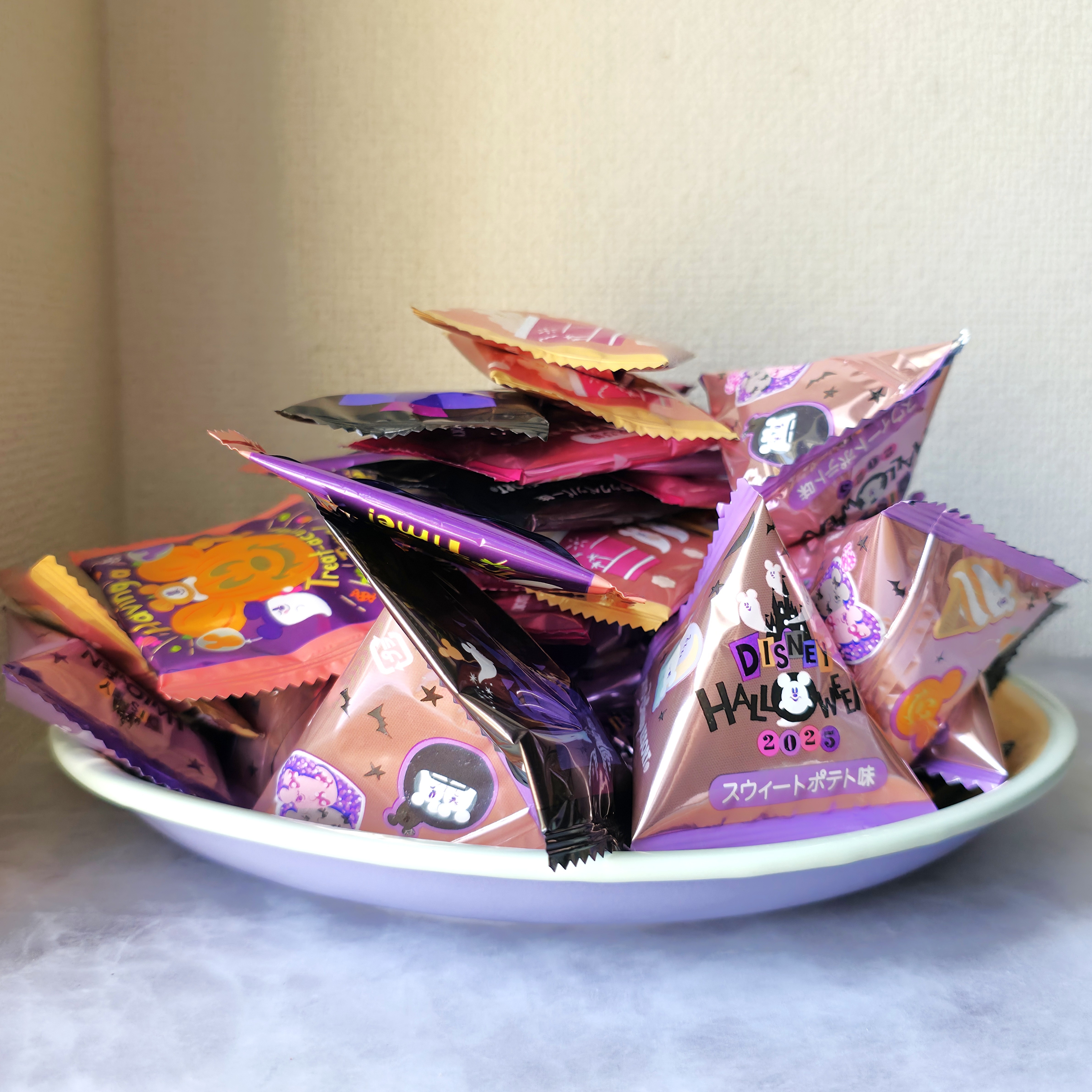 白い皿に盛られたディズニーハロウィーン2023のパッケージのキャンディ。