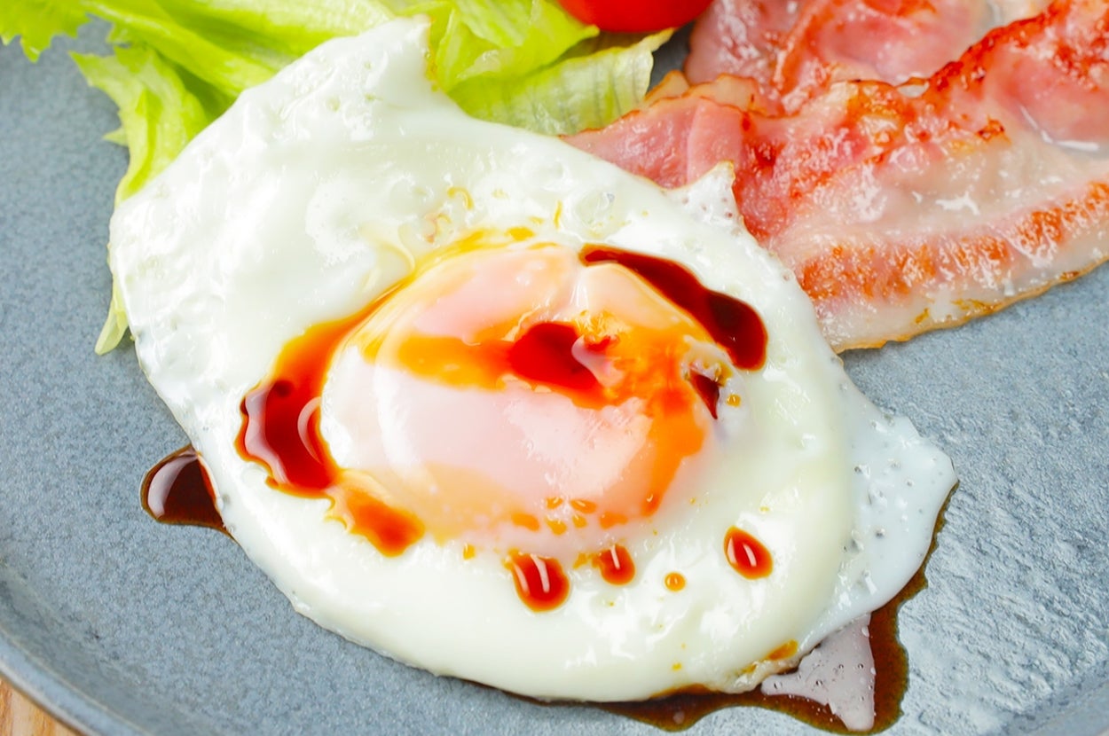 目玉焼きとベーコン、レタス、ミニトマトがプレートに盛られた朝食。