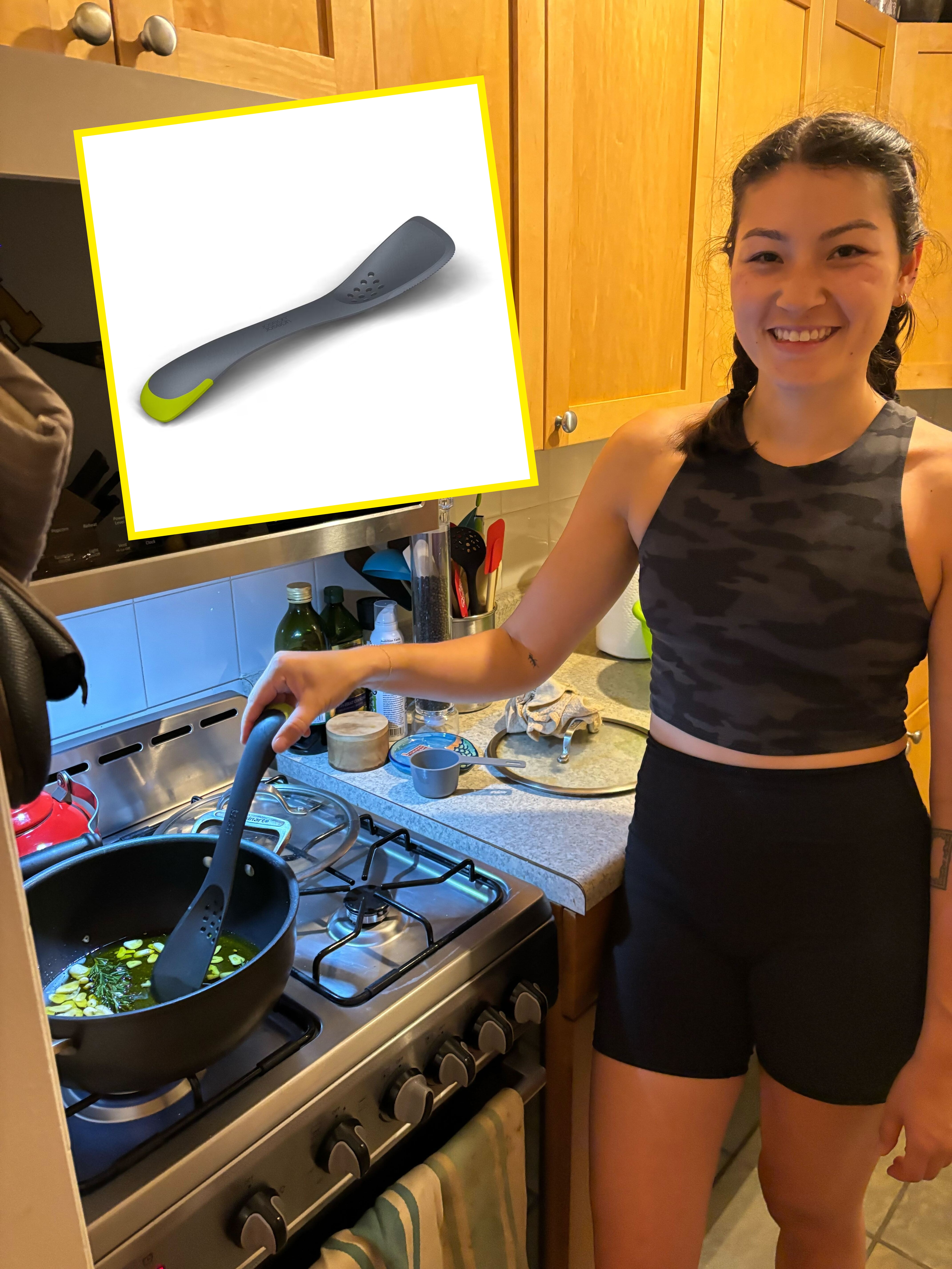 Person cooking vegetables in a pan on a stove, smiling at the camera, in a home kitchen