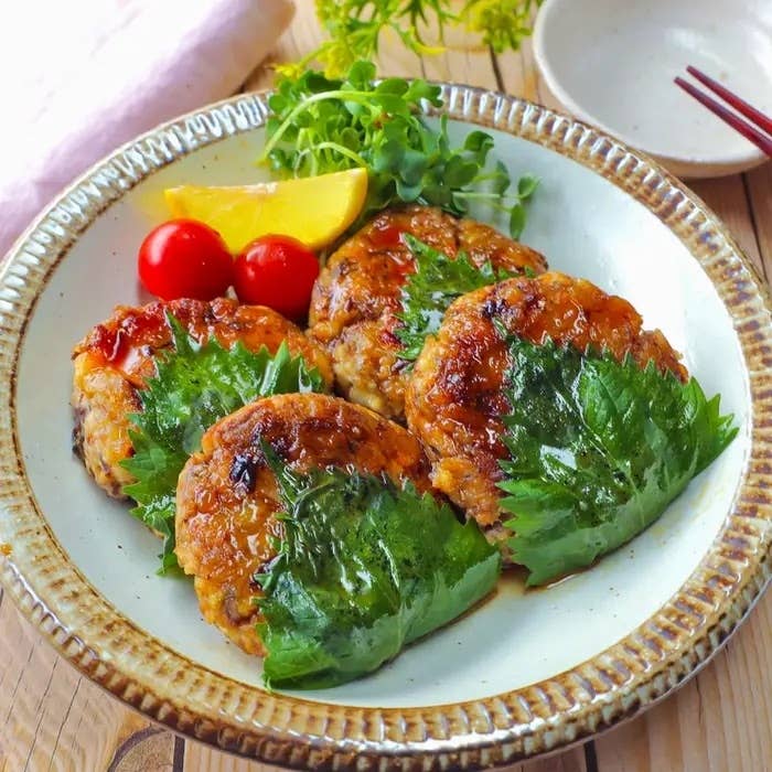 皿に盛られたシソで巻いたハンバーグ、トマトとレモン添え。