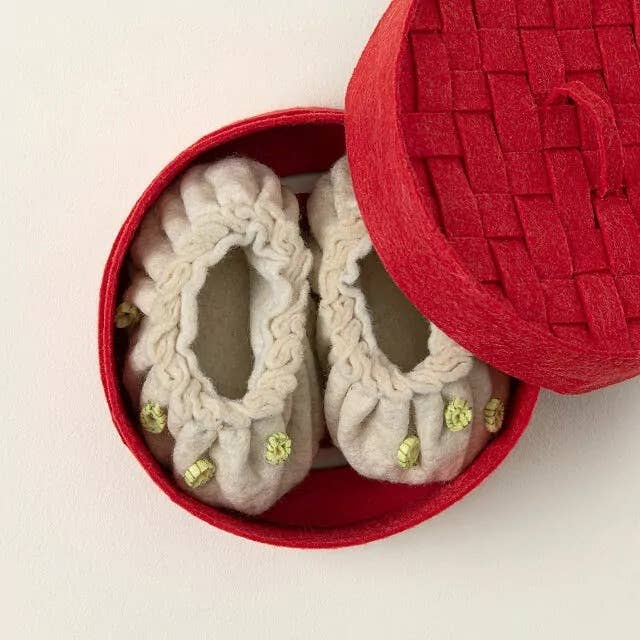 Small wool babe booties with greenish accents successful a round, open, textured reddish box