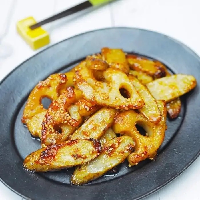 レンコンと野菜の炒め物が黒い皿に盛られている。