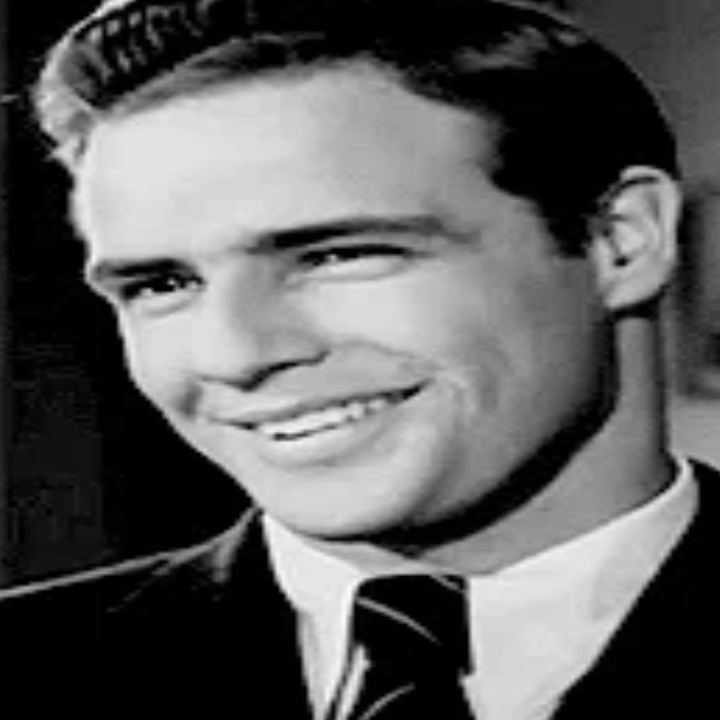 A smiling person in a suit and tie, posing indoors