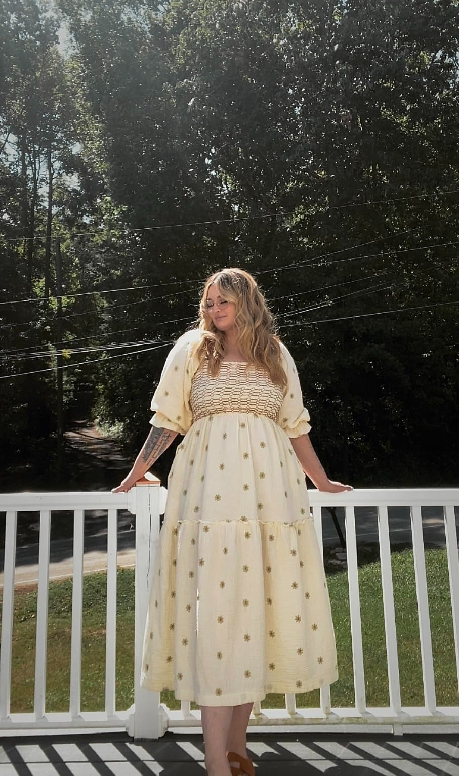 Person successful  a light, flowing formal  with floral patterns stands connected  a structure  overlooking a tree-lined area