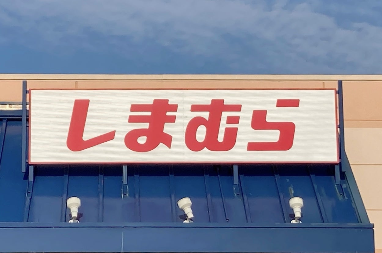 Store sign in Japanese script above an entrance with multiple lights and handicap parking sign visible