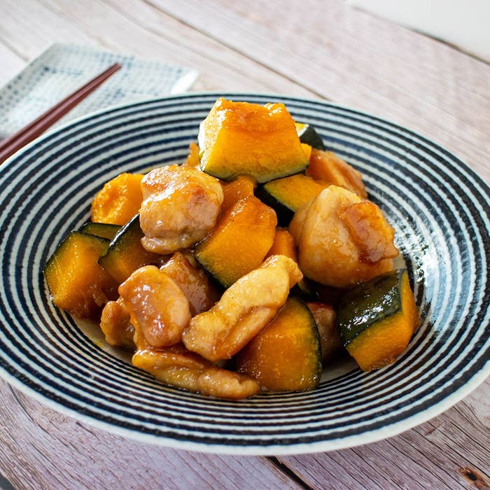 皿に盛られたカボチャと鶏肉の炒め物。食事用の箸が添えられた和風のセッティング。