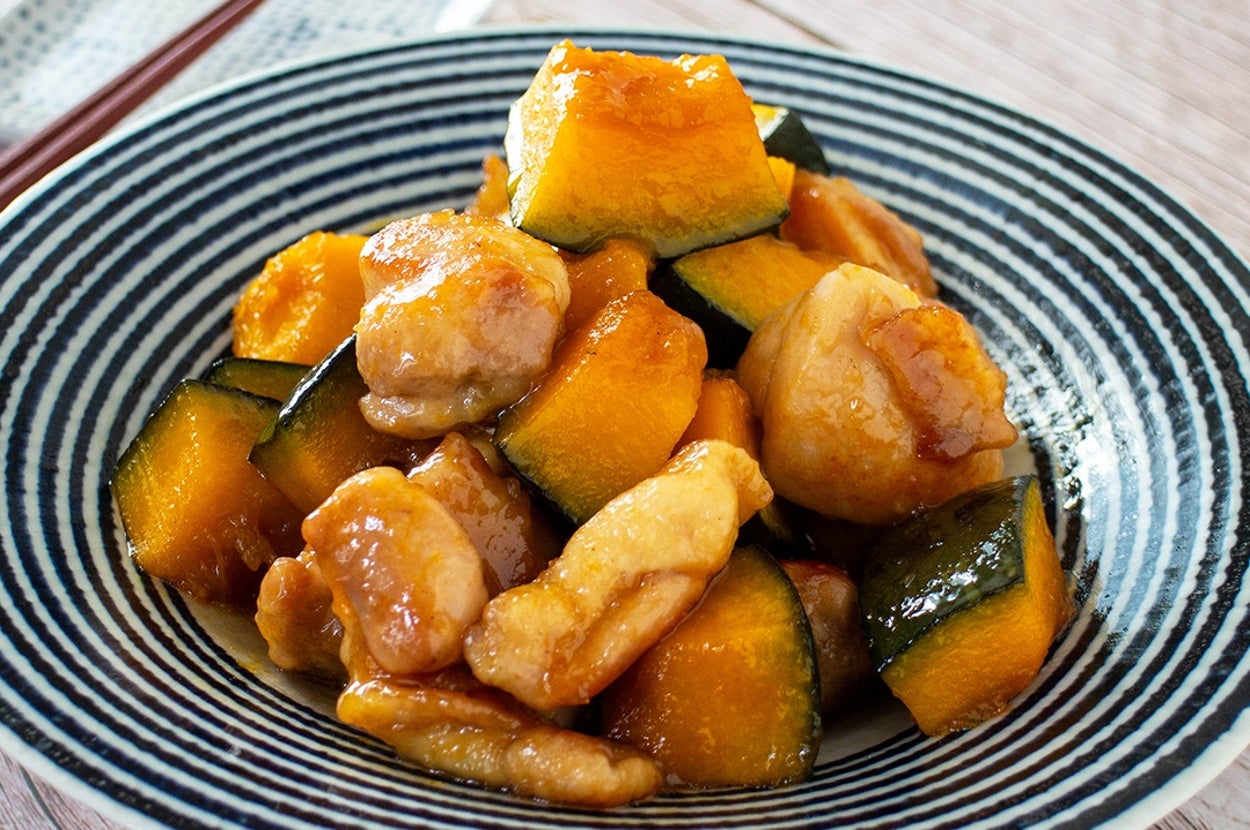 鶏肉とかぼちゃの照り焼き風炒めが盛られたボウル。後ろに箸。