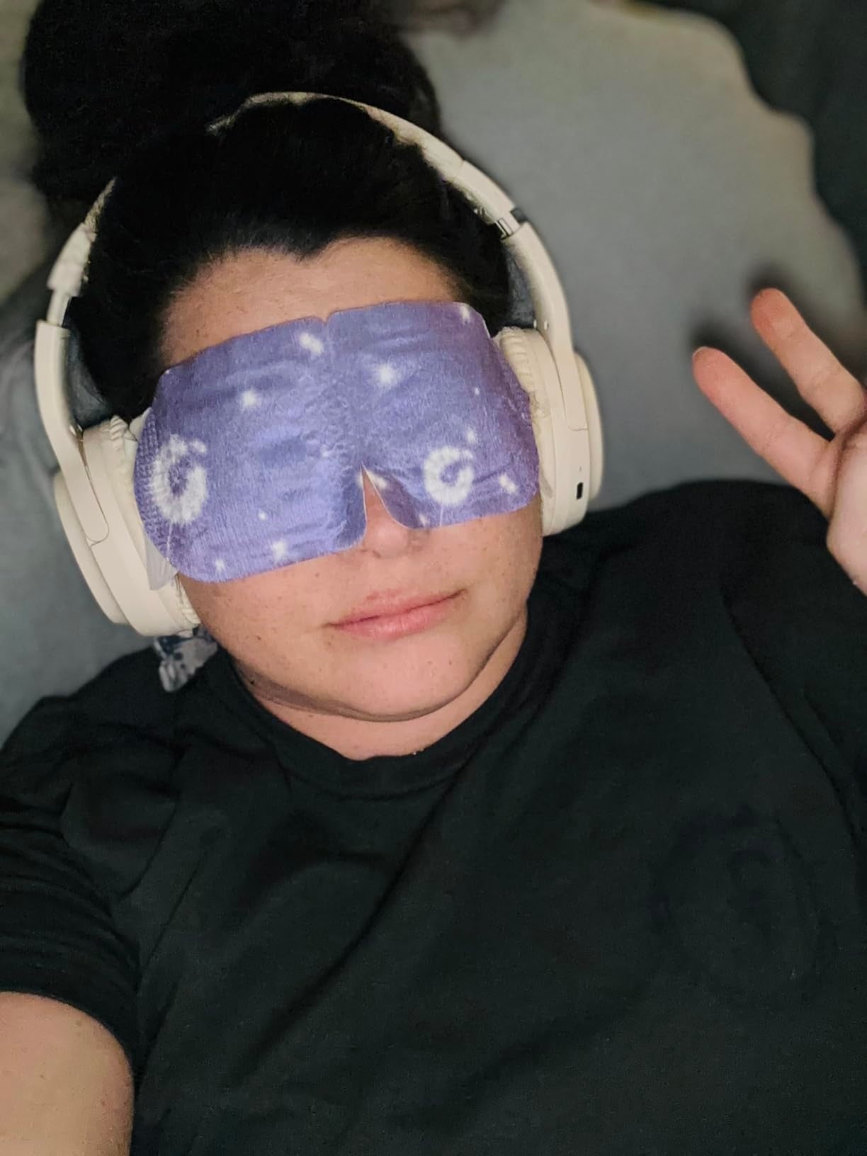 Person relaxing with headphones and a starry oculus  mask, giving a bid    sign. Ideal for self-care oregon  relaxation-themed buying  content