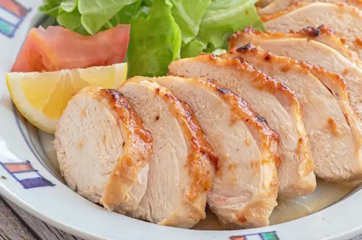 皿に盛られた焼き鳥のスライス、レタス、一切れのレモンとトマトが添えられている。