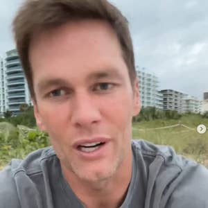 Person outdoors, wearing a casual T-shirt, with modern buildings in the background