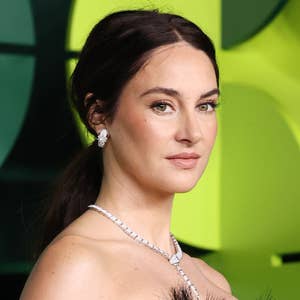 Person in elegant feathered dress with diamond necklace poses confidently at a formal event