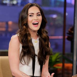 Person smiling and seated during a talk show interview, wearing a sleeveless dress with sequin details