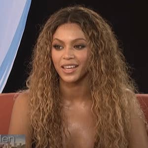 Celebrity with long wavy hair, wearing a low-cut top, smiling during an interview on a talk show set