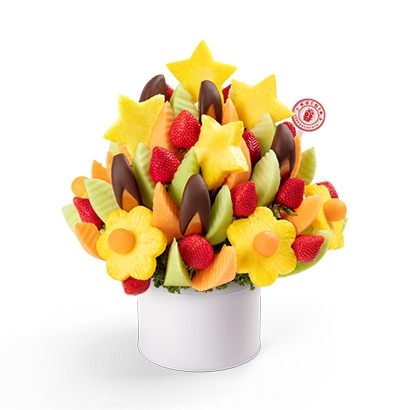 Fruit bouquet with pineapple stars and flowers, chocolate-dipped bananas, strawberries, and melon wedges, arranged in a white container