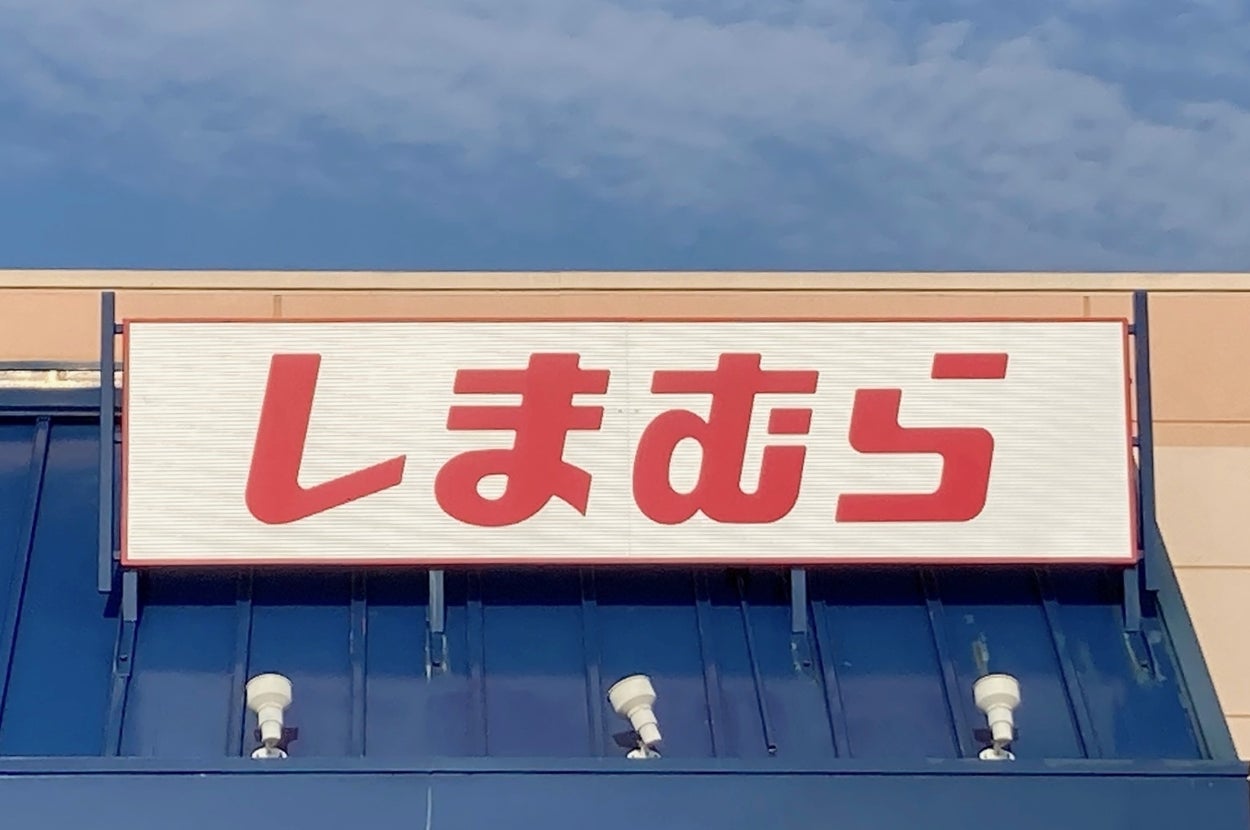 Storefront with a red and white sign displaying Japanese characters above blue awning