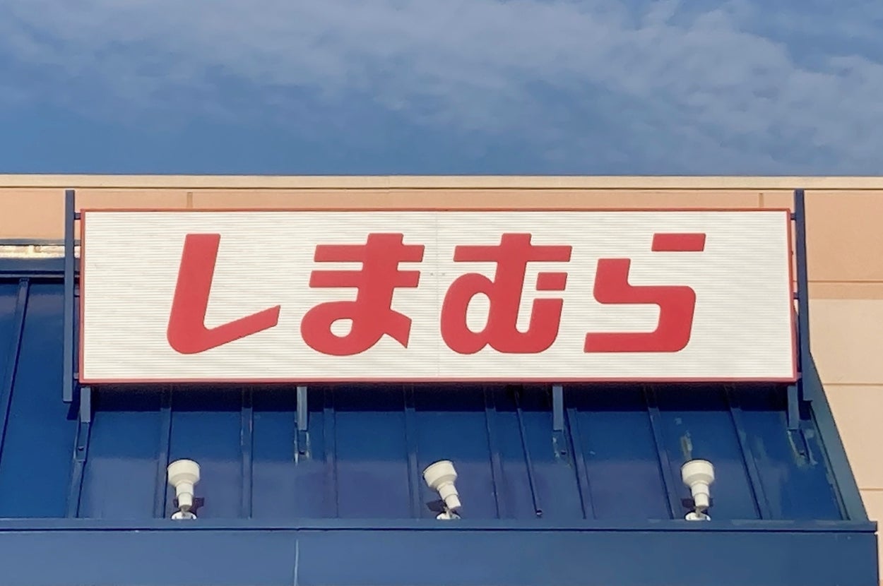 Storefront with a sign displaying Japanese text "しまむら" above blue awning