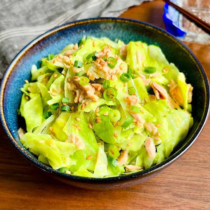 キャベツの和え物が器に盛られている。刻んだネギとゴマでトッピングされ、美味しそうな仕上がり。