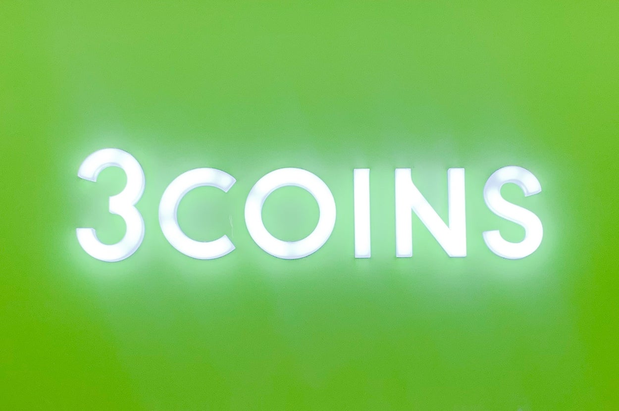 お店の看板に「3COINS」と書かれている。ディスプレイに割引チラシが多数掲示されている。