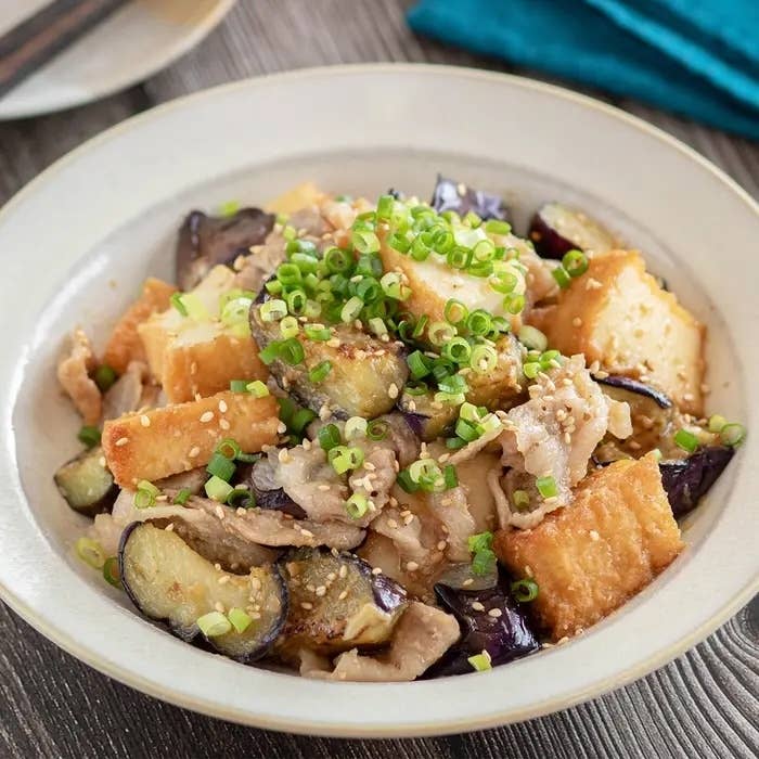 お皿に盛られた野菜と豆腐の炒め物。ネギとゴマがトッピングされた食欲をそそる料理。