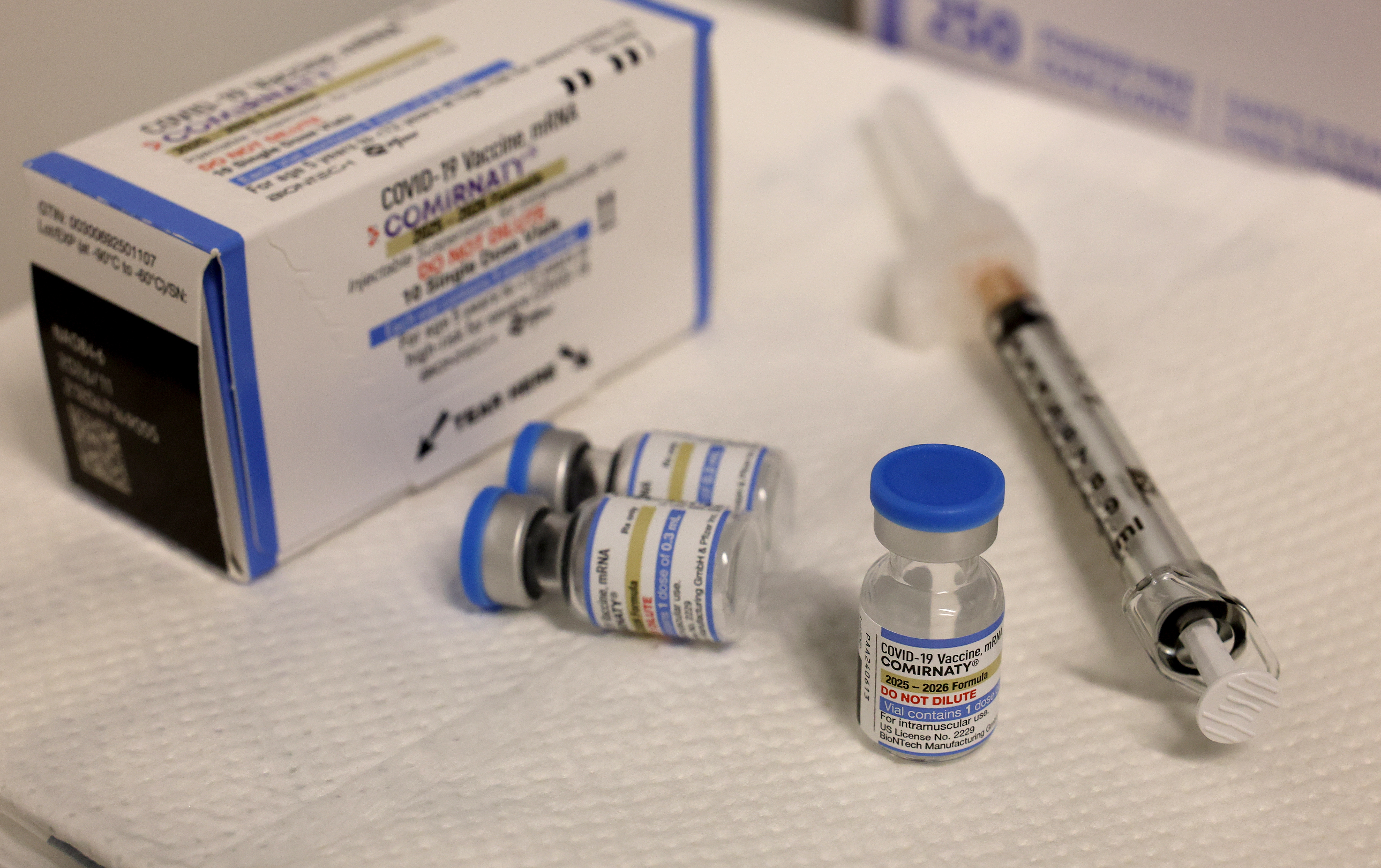 COVID-19 vaccine box, vials, and syringe connected a table