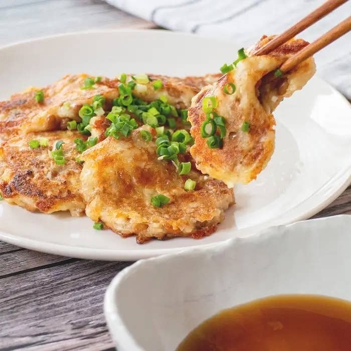 餃子の皮で作られたスナック風の料理が皿に盛られ、刻んだネギがトッピングされています。横にはつけだれの器があります。