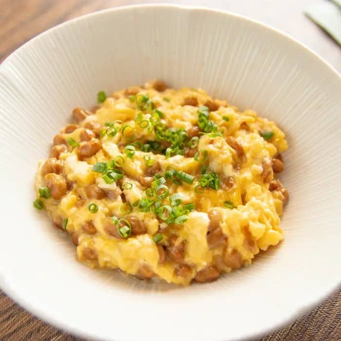 クリーミーな卵納豆ご飯が白いボウルに盛られ、小ねぎが散らされている。