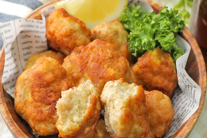 ボウルに鶏肉のナゲットが盛られ、レモンとレタスが添えられている。背景には新聞紙が敷かれている。