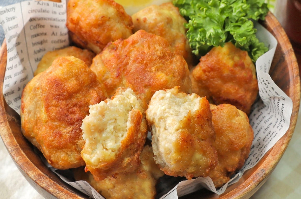 ボウルに鶏肉のナゲットが盛られ、レモンとレタスが添えられている。背景には新聞紙が敷かれている。