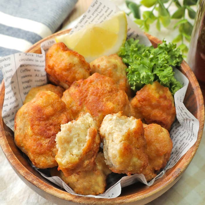ボウルに鶏肉のナゲットが盛られ、レモンとレタスが添えられている。背景には新聞紙が敷かれている。