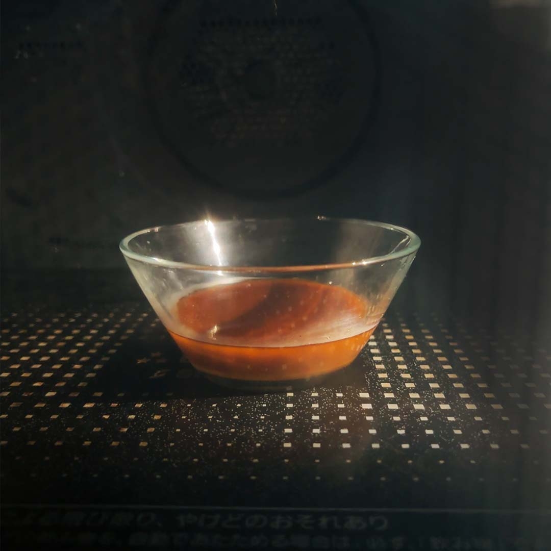 電子レンジの中にある透明なガラスボウルに少量のソース。