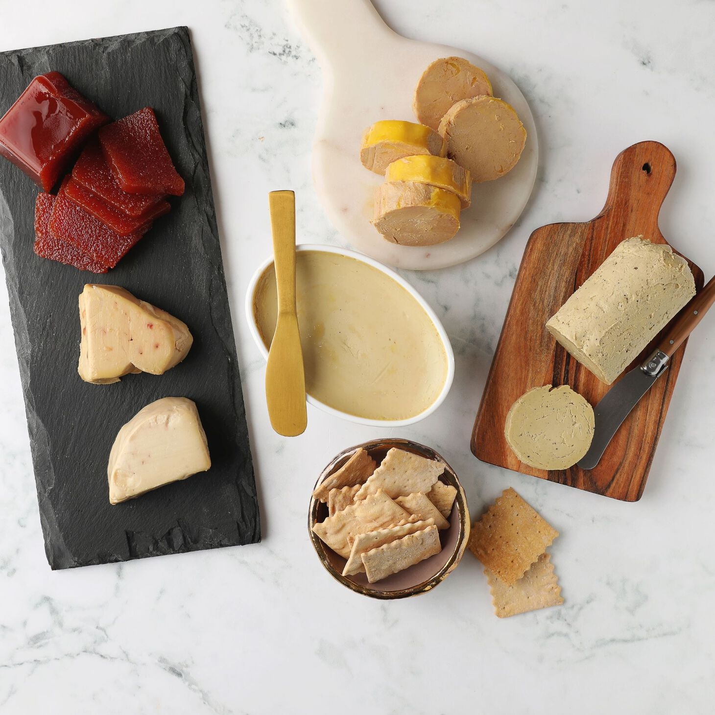 Assorted gourmet cheeses and spreads displayed on a marble surface with crackers, perfect for elegant home entertaining