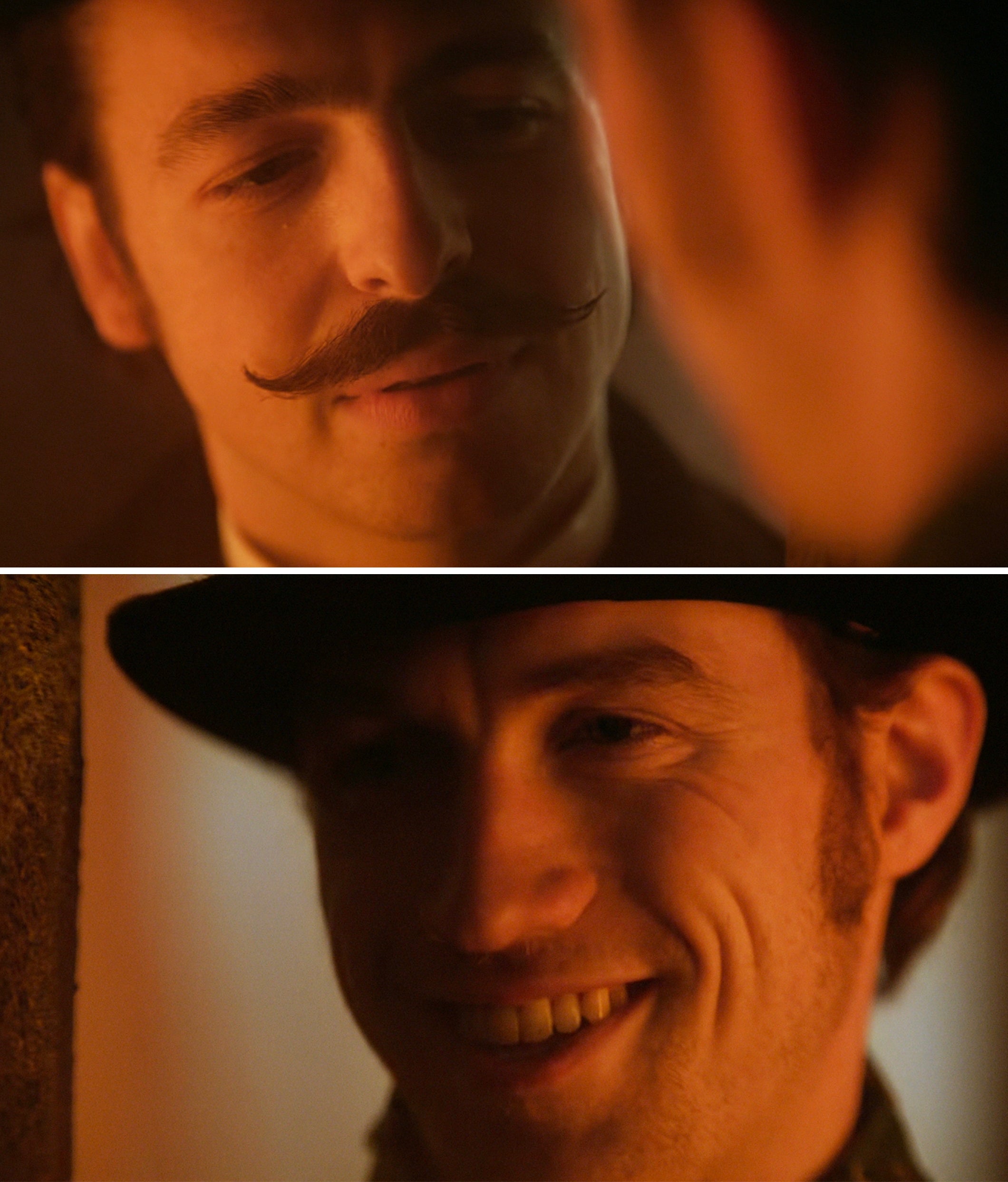 Two people in a dimly lit setting, one with a mustache and another with a hat, sharing a close conversation with slight smiles