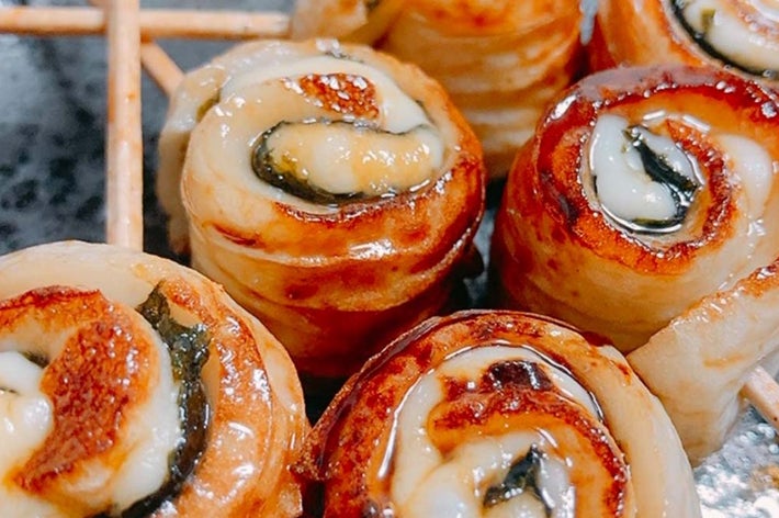 日本の焼き鳥風串焼き料理、ベーコンに巻かれたチーズがトッピングされたロール型。